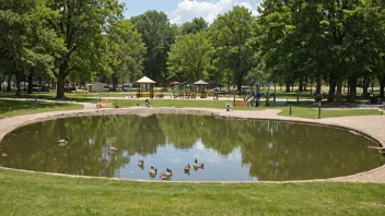 En familiepark med lekeplass, piknikbord og en dam med ender.