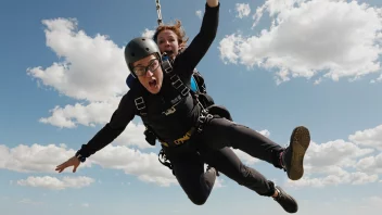 En person i fritt fall, med en fallskjerm eller bungeejump-kabel festet, med et uttrykk av spenning og fryd på ansiktet.