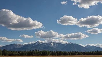 En fin dag med en klar blå himmel og noen hvite skyer, med et fjellområde i bakgrunnen.