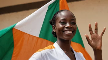 En person fra Elfenbenskysten, smiler og vinker, med et bakgrunn av den ivorianske flagget