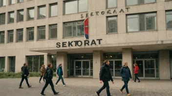 En stor bygning med en skilt som leser 'Sektoretat' på norsk, med mennesker som går inn og ut av bygningen, omgitt av en by.