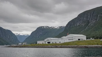 En fabrikkbygning med en skilt som leser 'Foreedlinsbedrift' på norsk, beliggende i et naturskjønt fjordlandskap.