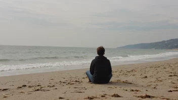 En person sitter alene på en strand, tapt i tanker.