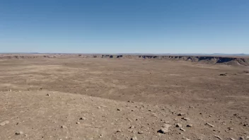 En flat terrengformasjon med en klar blå himmel i bakgrunnen.