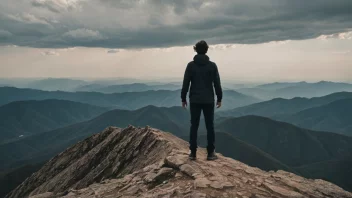 En person som står på et fjelltopp med en sterk vind som blåser, symboliserer å overvinne utfordringer.