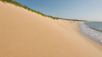 En sandstrand med en naturlig barriere i bakgrunnen.