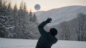 En person kaster en snøball i et vinterlandskap med snødekte trær og en klar blå himmel