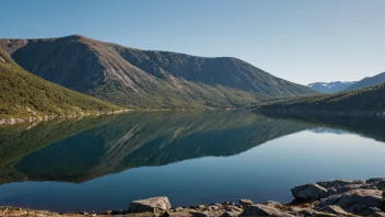 Et majestetisk fjell i Norge med en rolig innsjø og en klar himmel.