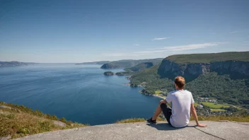 En person som står på en stein og ser ut over havet, med et stort smil på ansiktet og et kamera i hånden.