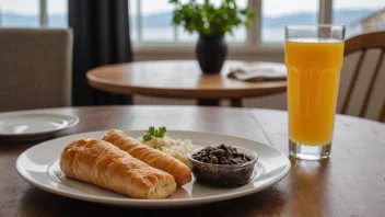 Et glass surkålsaft på et bord med en tallerken tradisjonell norsk mat i bakgrunnen.