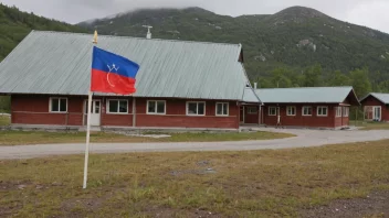 En samisk skolebygning med et tradisjonelt samisk flagg og en skilt med skolens navn på samisk.