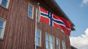 En riggstolpe, en del av en bygning, med et norsk flagg i bakgrunnen.