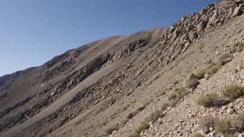 Et bilde av et bratt fjell eller en ås med en steinete overflate og sparsom vegetasjon