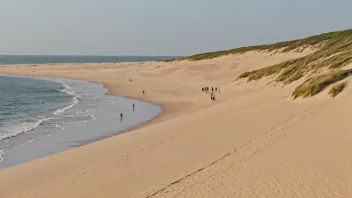 Et fredelig bilde av en sandstrand med sanddyner og noen mennesker som går i det fjerne.